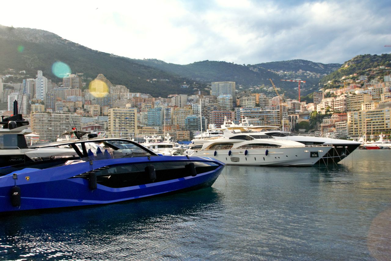 Stunning view of luxury yachts moored in Monaco harbor with cityscape and hills in the background.